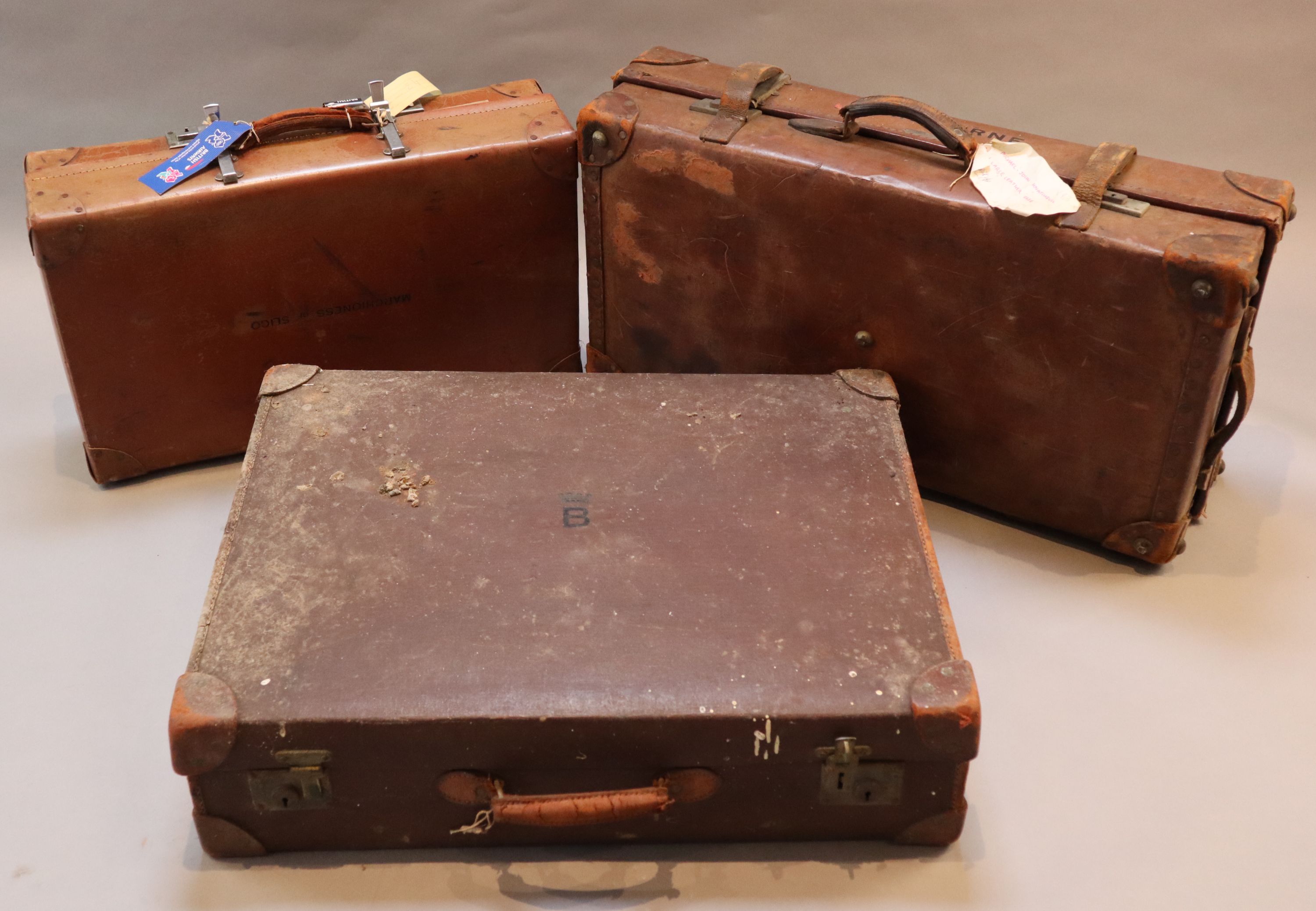 A group of three tan leather suitcases, one inscribed Brabourne, another Marchioness of Sligo